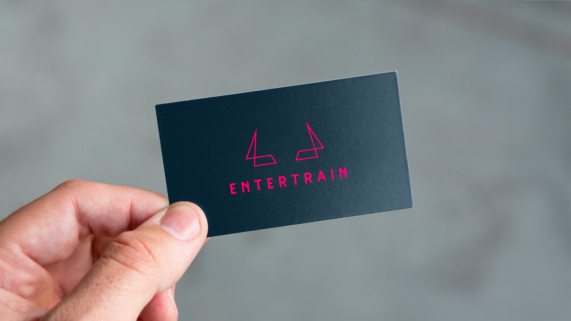 Une photo d'une main tenant la carte de visite de Entertrain coaching.