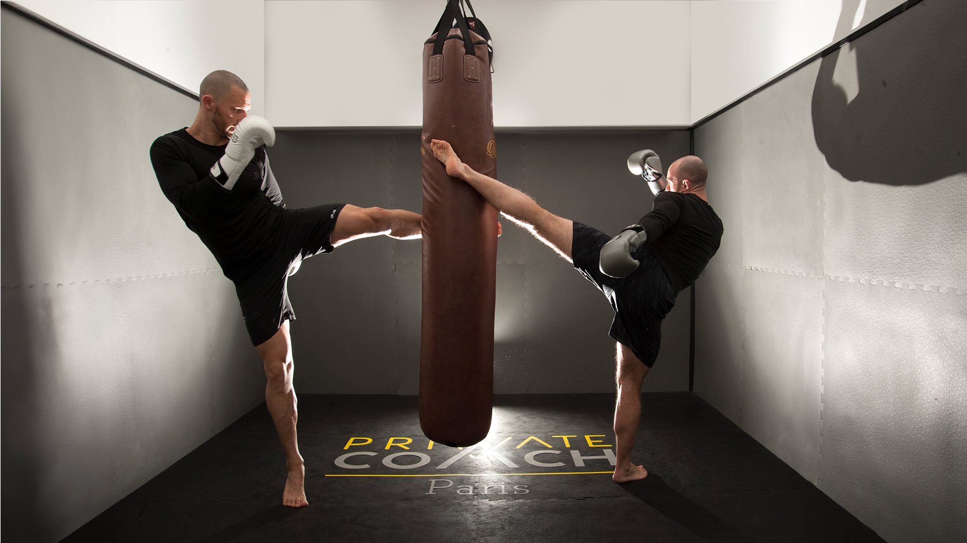 Deux boxeurs s'entraînant dans une salle de boxe avec le logo Private Coach imprimé sur le sol.